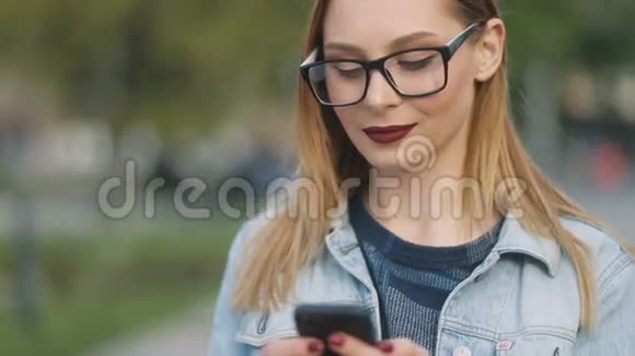 迷人的女孩红唇使用智能手机在欧洲城市嬉皮士女孩用手机上网发短信视频的预览图