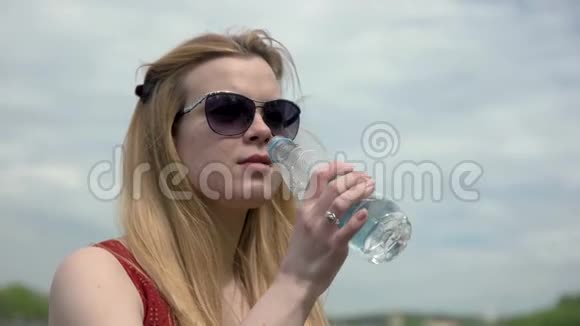 肖像年轻女子在炎热的夏天从塑料瓶里喝冷水视频的预览图