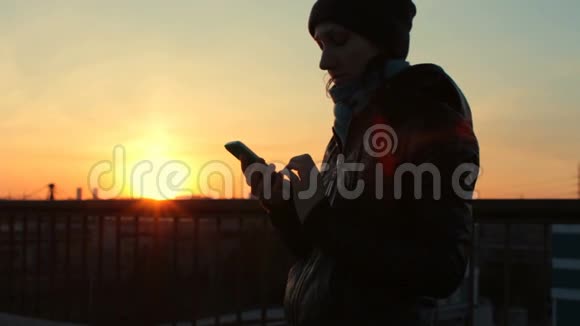 日落时分在城市桥上用手机的年轻美女视频的预览图