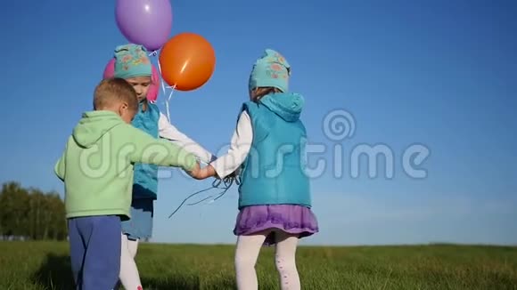 快乐的孩子们拿着气球在公园里手拉手盘旋视频的预览图