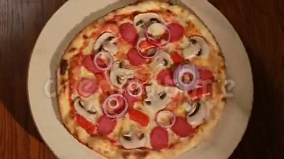 新鲜出炉的意大利腊肠蘑菇洋葱和胡椒粉的比萨饼转过来顶部视图视频的预览图