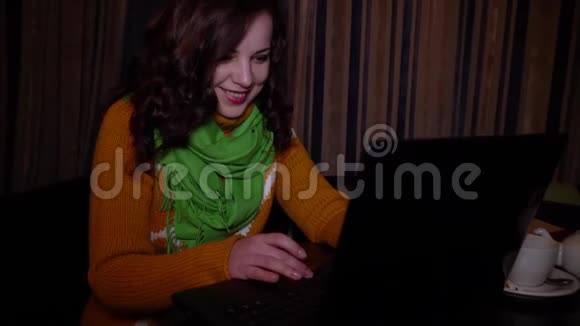年轻漂亮的女孩坐在咖啡馆的桌子上喜欢笔记本电脑她微笑着特写镜头视频的预览图