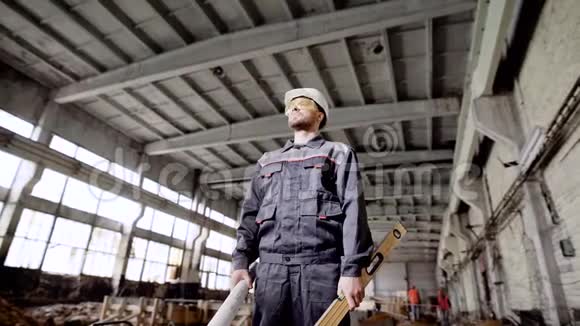年轻的工头站在建筑工厂背景是焊接工人持有施工计划视频的预览图