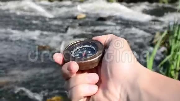 人手拿着指南针在暴风雨的河流的背景上视频的预览图