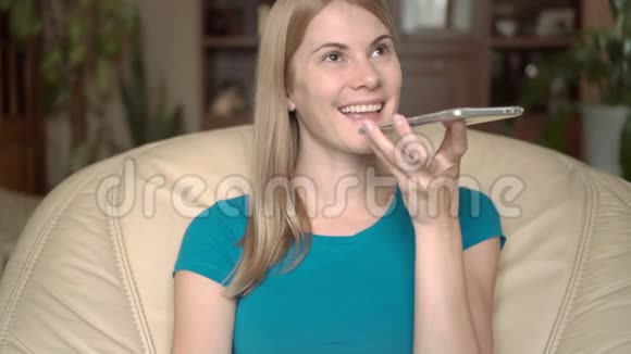 热情快乐的年轻女子坐在家里的椅子上用她的智能手机和朋友聊天视频的预览图