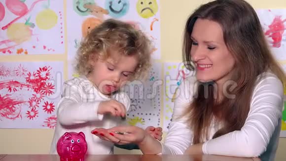 快乐的白种人女人和女孩把硬币放进储蓄罐视频的预览图