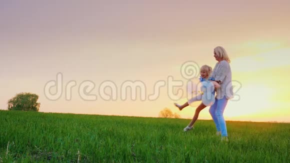 无忧无虑的妈妈和女儿在风景如画的地方玩耍在一片绿色的大草地上地平线上有一棵孤独的树视频的预览图