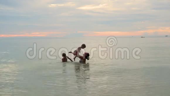 女孩和孩子们在海里游泳和玩耍日落时间视频的预览图