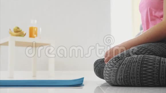 一位年轻漂亮的女士穿着蓝色慢跑或健身垫在家工作后在客厅里关门视频的预览图