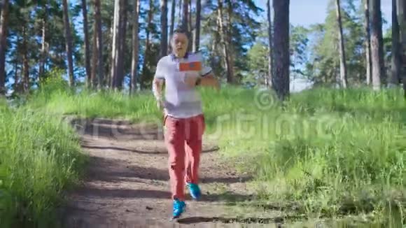 一个成年男子在一个温暖的夏日积极地沿着森林小径奔跑穿运动鞋的人从事户外活动视频的预览图