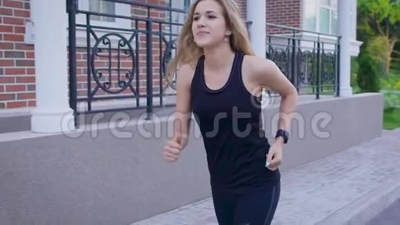 慢镜头拍摄一位年轻的女士她的头发掉了下来她在一个夏天沿着街跑视频的预览图