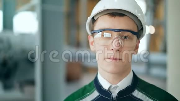 年轻工程师戴着防护头盔在现代化工厂里摆着相机视频的预览图