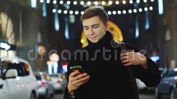 一个年轻人走在街上看短信视频的预览图