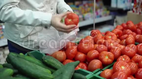 年轻女子选择成熟的红西红柿在超市买新鲜蔬菜视频的预览图