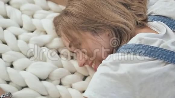 一个年轻的女孩躺在公园里的美利奴白色毯子上享受夏天的天气视频的预览图