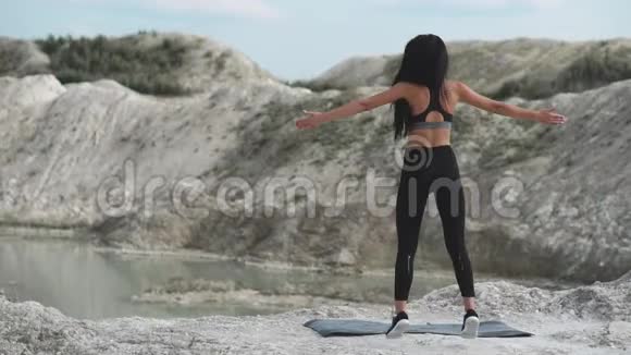穿着黑色运动服的运动型黑发女孩在一个蓝水白垩沙场上训练打嗝视频的预览图
