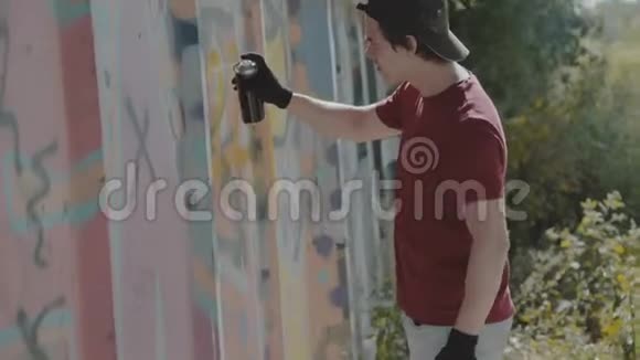 小男孩偷偷地在街墙上画五颜六色的涂鸦4K视频的预览图