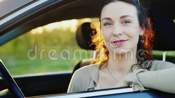 一位年轻女司机的慢动作视频肖像透过窗户看着摄像机微笑着视频的预览图