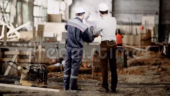 两个人站在建筑区域看未来结构的施工图领班视频的预览图