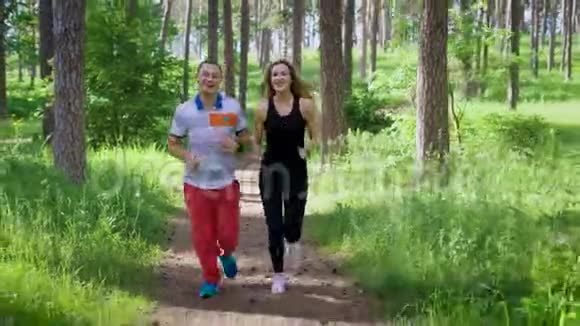 一男一女穿着跑鞋在夏日公园里阳光明媚的一天沿着小路奔跑夫妻双方在积极交谈视频的预览图