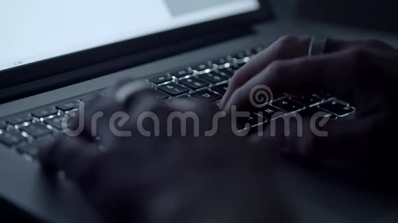 一个男人在黑暗的房间里对着笔记本电脑打字视频的预览图