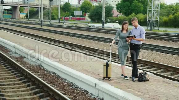 站台上的两个商人正在等他们的火车他们用平板电脑站在铁路附近视频的预览图
