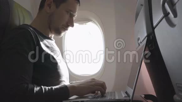 在飞机上用笔记本电脑的年轻人视频的预览图