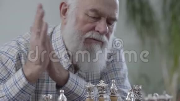成熟男人的肖像思考哪一个棋子要做一个动作两个人坐在家里下棋视频的预览图