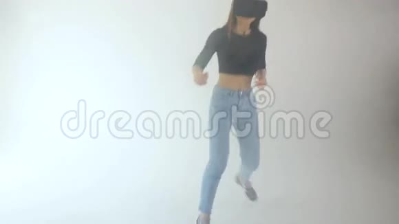 一个女孩戴着虚拟现实耳机和跳跃白色背景和烟雾4K视频的预览图