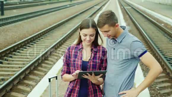 一对年轻的游客在火车站使用平板电脑机票在线开始了美好的假期视频的预览图