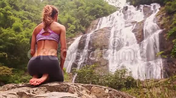 女孩坐在瑜伽姿势前瀑布特写视频的预览图
