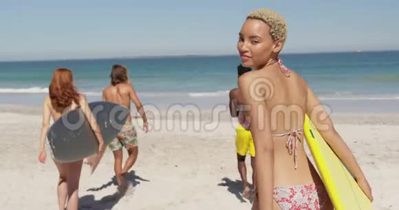 沙滩上带冲浪板的年轻成年朋友视频的预览图