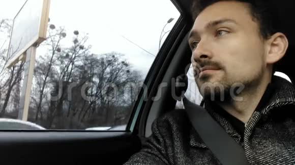 有魅力的男人坐在车里看着窗外视频的预览图