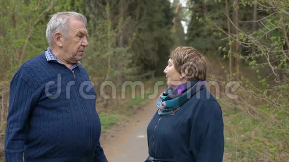 一对美丽的老年夫妇在公园里散步亲切地交谈好心情积极生活慢动作视频的预览图