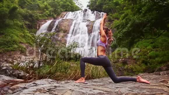 女孩拿着瑜伽姿势双手举着头对着瀑布视频的预览图