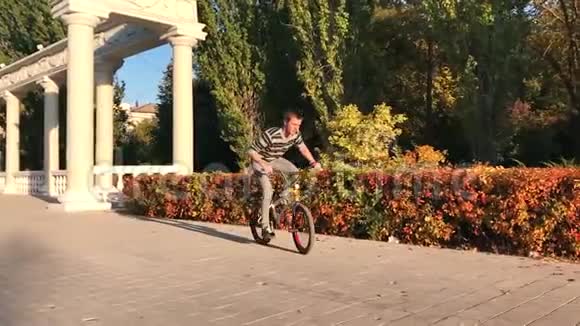 夏天在一个阳光明媚的公园里自行车爱好者们骑着自行车跳跃年轻的自行车手BMX制造奥利玩具和骑自行车视频的预览图