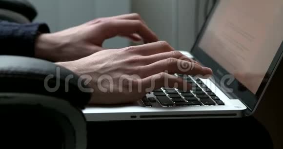 侧视图一名男子在笔记本电脑上打字的手持录像视频的预览图