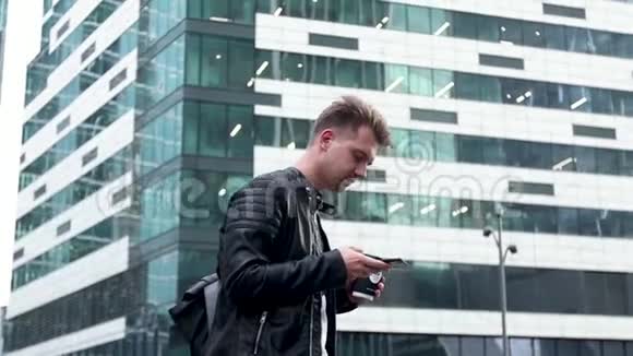 英俊的年轻人在街上使用他的智能手机视频的预览图