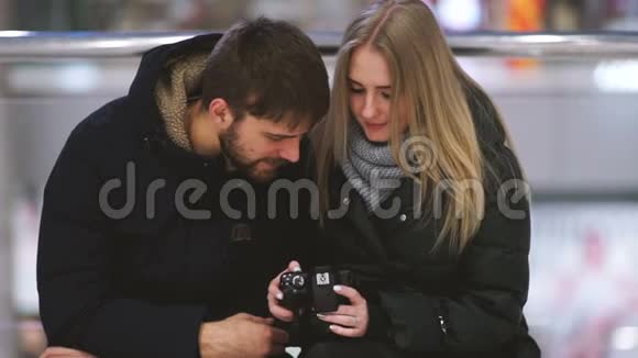 年轻有魅力的情侣在购物中心用相机观看照片视频的预览图