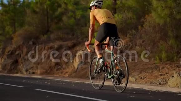 戴着头盔和运动装备的职业自行车运动员骑在山路上视频的预览图