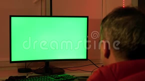一个男人在他的家庭办公室在一个绿色的电脑屏幕前在家工作视频的预览图