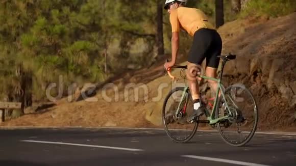 戴着头盔和运动装备的职业自行车运动员骑在山路上视频的预览图