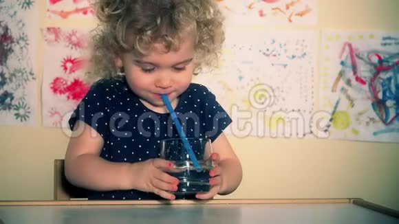 小可爱的孩子用吸管把空气吹进玻璃杯里视频的预览图