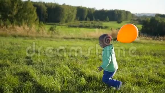 快乐男孩带着气球在公园里跑步散步和户外娱乐视频的预览图