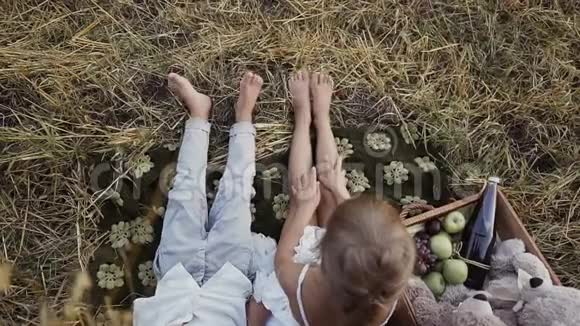 两个年幼的孩子赤着脚坐在稻草堆下的田野里一个男孩和一个女孩吃水果视频的预览图