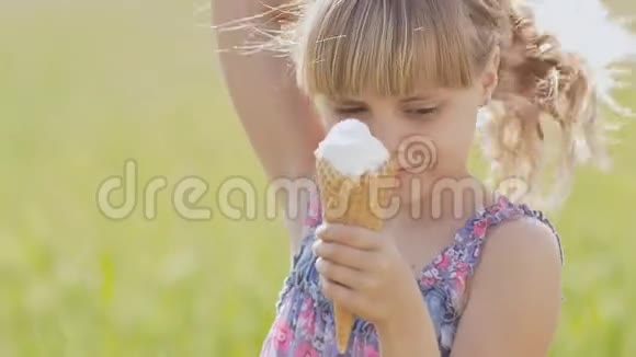 美丽的金发小女孩在麦田的背景下夏天吃冰淇淋温暖的晴天视频的预览图