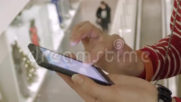 圣诞节前女人在购物中心使用智能手机视频的预览图