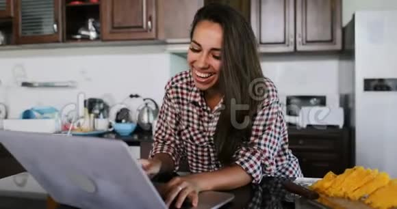 女孩用笔记本电脑在厨房聊天在线年轻女子工作室现代室内视频的预览图