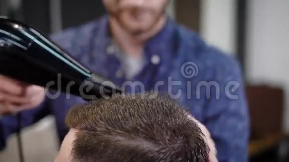 一个来到理发店的人的头部近距离拍摄理发师在温暖的帮助下把顾客头擦干视频的预览图