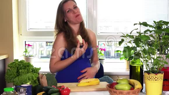 怀孕时间营养孕妇坐在厨房桌子旁吃香蕉视频的预览图